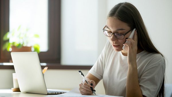 Frau am Telefon macht Notizen